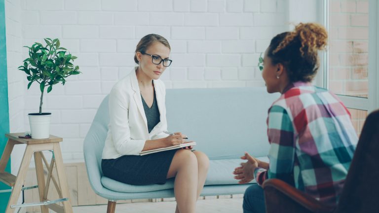 Therapist taking notes while talking with a patient in a counseling session
