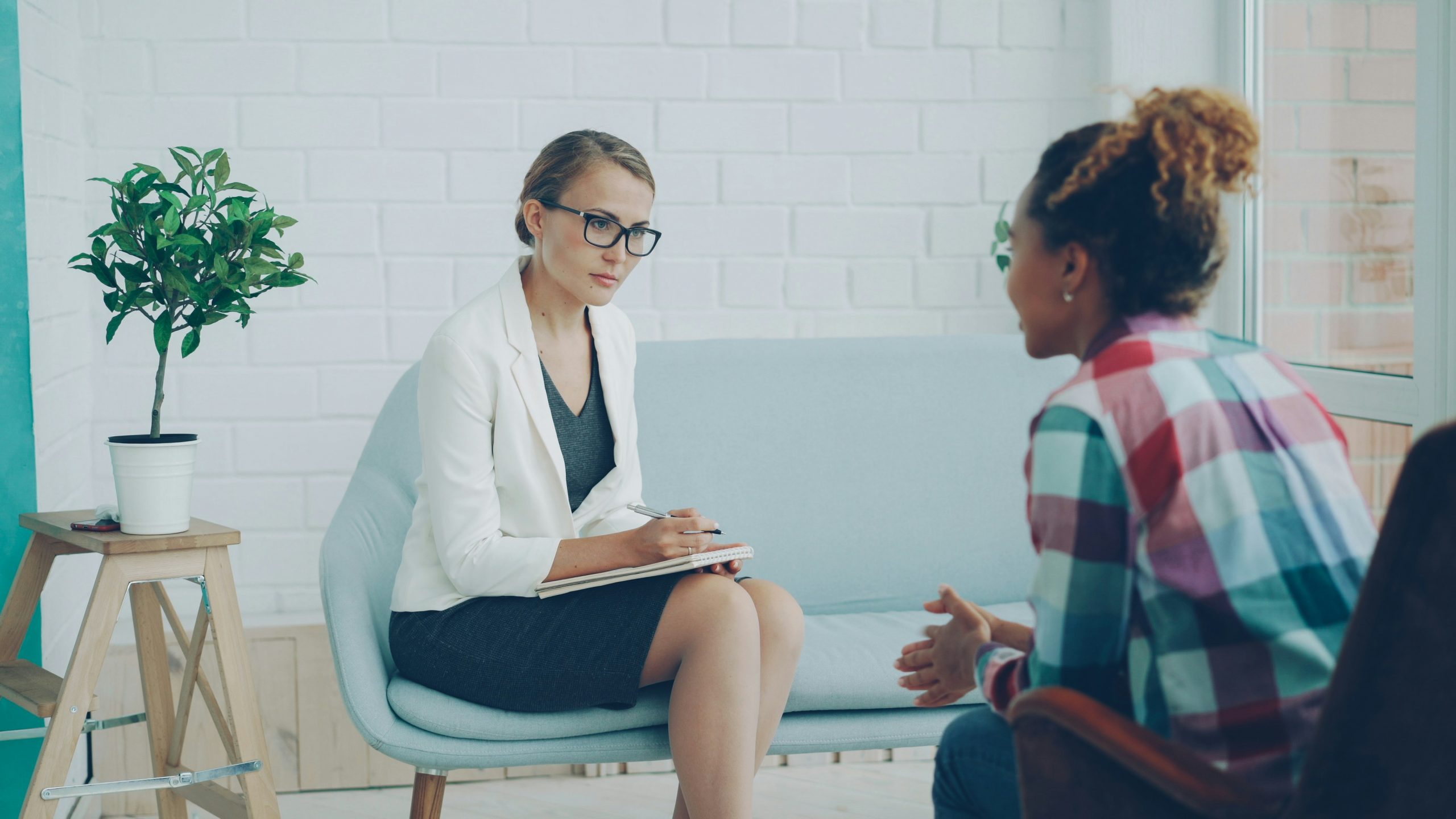 Therapist taking notes while talking with a patient in a counseling session