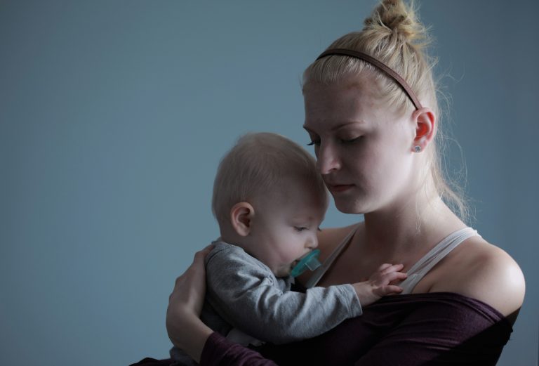 A mother holding a baby with a pacifier