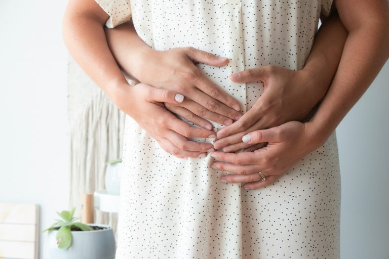 Two people holding a pregnant belly