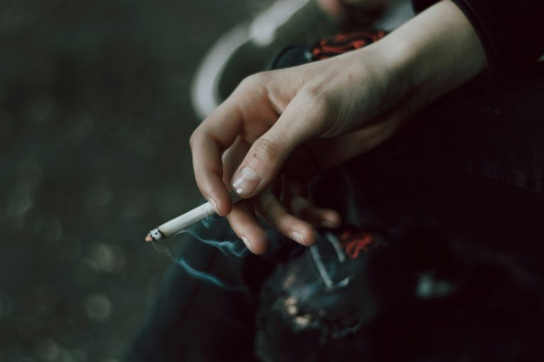 Hand holding a lit cigarette